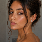 Close-up of a woman with styled hair and jewelry against a neutral background