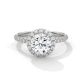 Round cut diamond halo engagement ring in white gold with a pavé diamond band, shown in a front product view.
