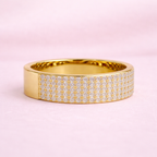 Gold ring with diamond accents on a pink background