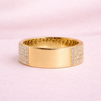 Gold ring with diamond accents on a pink background