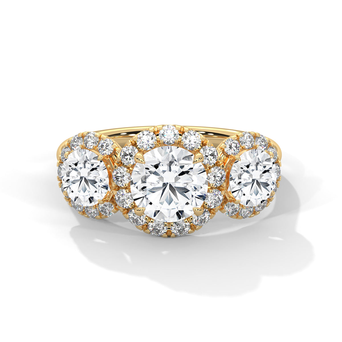 Three-stone round cut diamond engagement ring in yellow gold with diamond halos around the center and side stones, shown in a front product view.