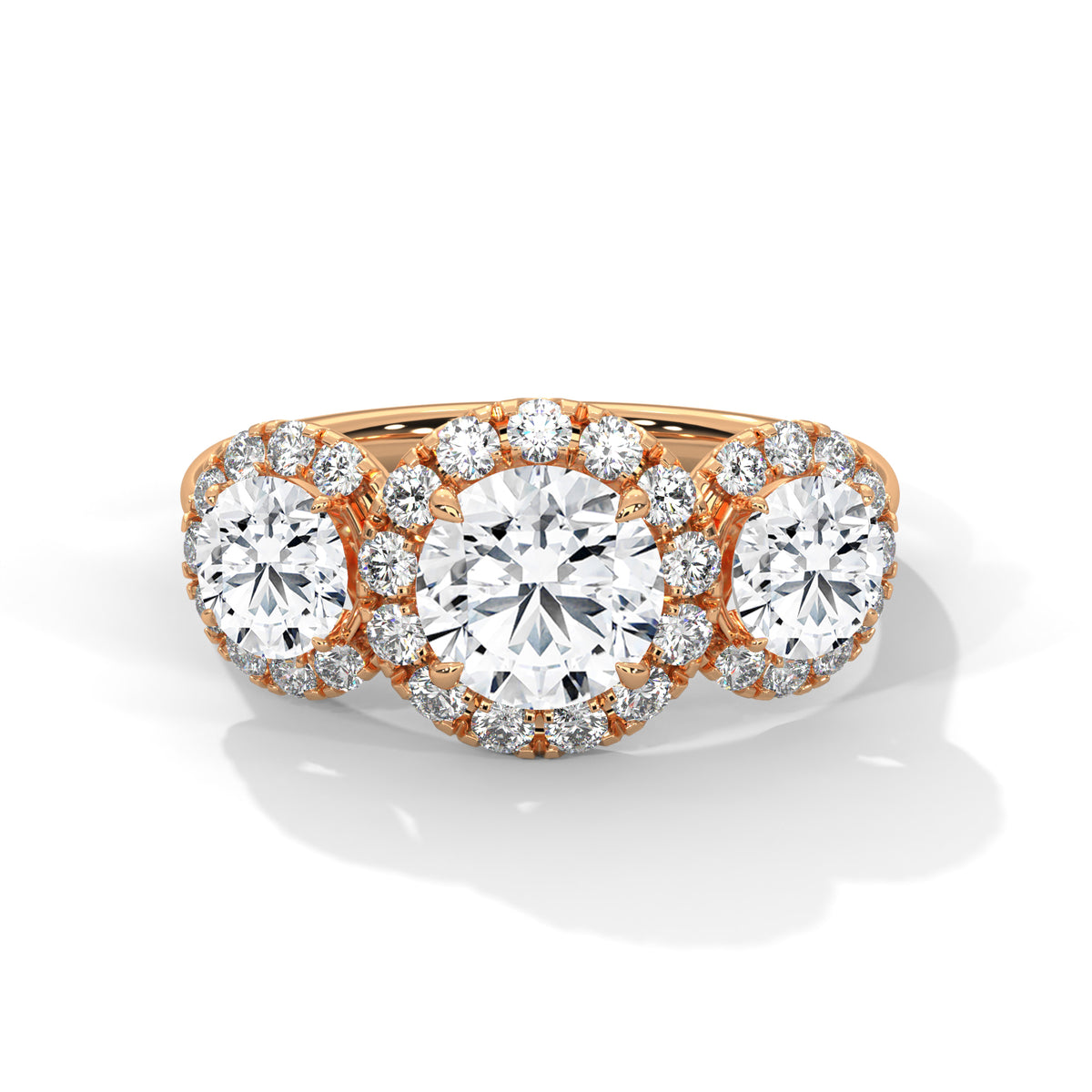 Three-stone round cut diamond engagement ring in rose gold with diamond halos around the center and side stones, shown in a front product view.