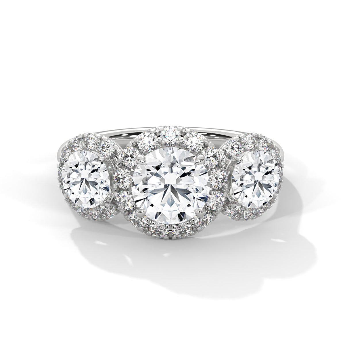 Three-stone round cut diamond engagement ring in white gold with diamond halos around the center and side stones, shown in a front product view.