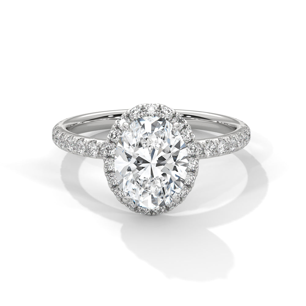 Oval cut diamond halo engagement ring in white gold with a pavé diamond band, shown in a front product view.