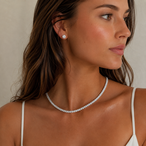 Woman wearing a silver necklace and earrings against a neutral background
