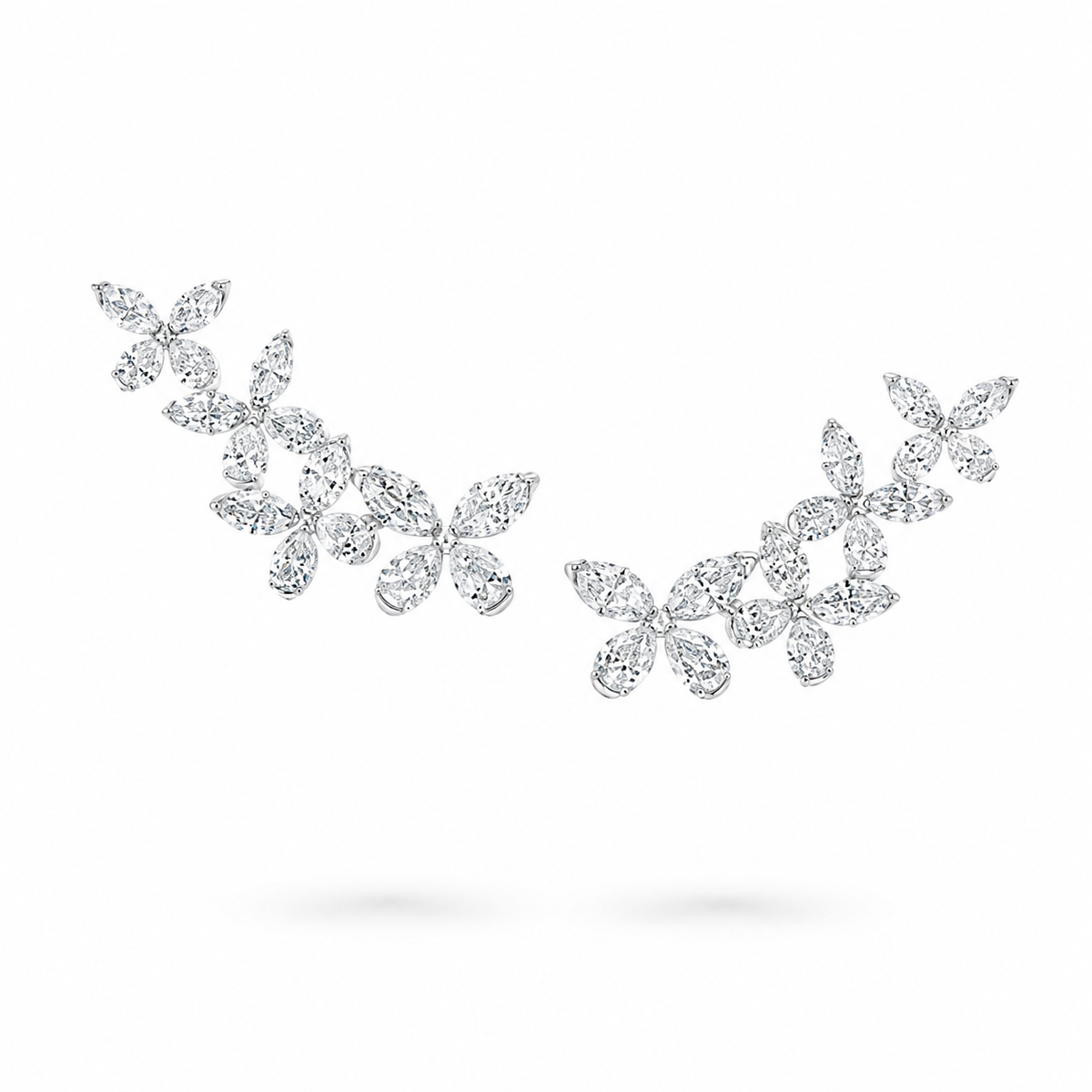 Silver-toned leaf cluster stud earrings set with clear marquise and round-cut gemstones, arranged in two separate pieces on a white background.