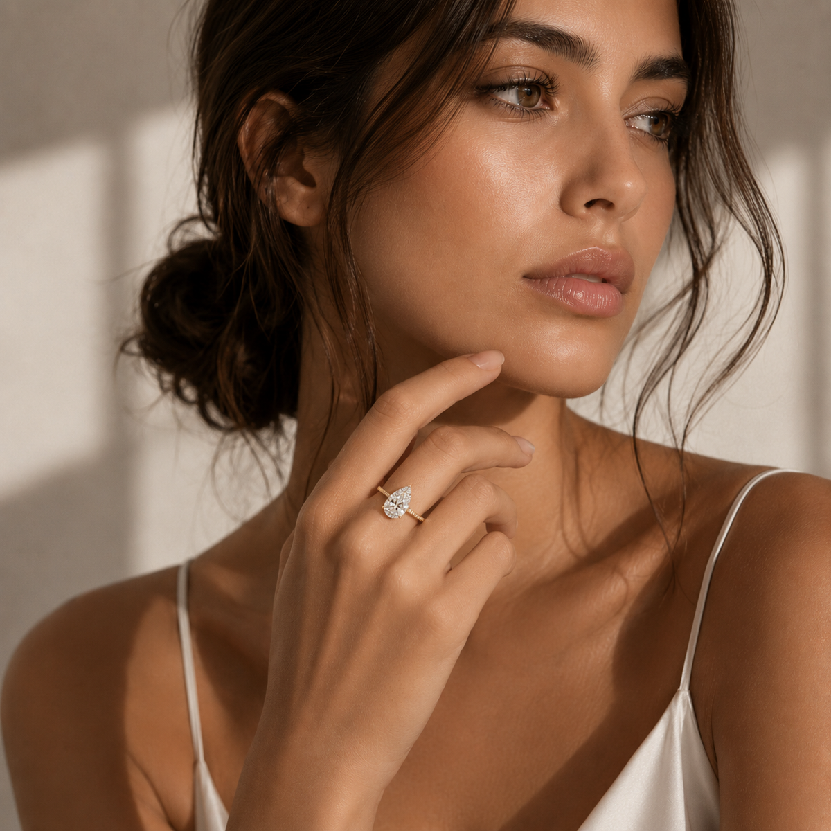A woman wear a 2.1 carat lab-grown pear-shaped diamond hidden halo yellow gold ring.
