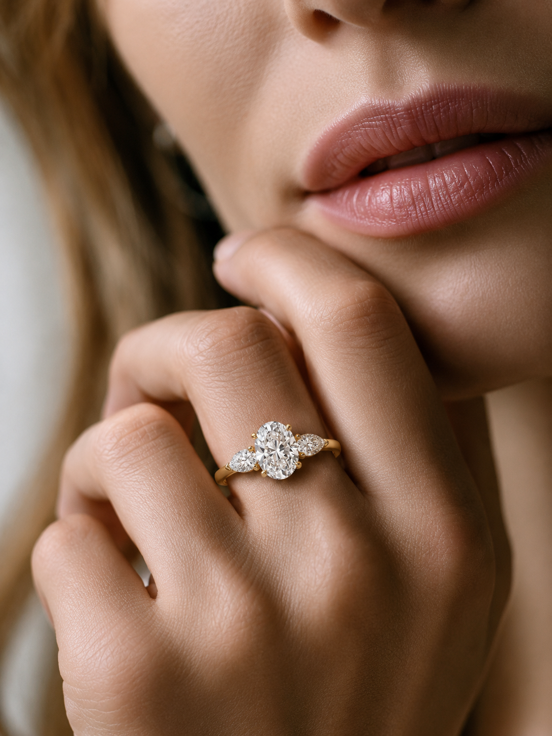 A woman wearing 3 carat oval lab-grown diamond three-stone engagement ring.