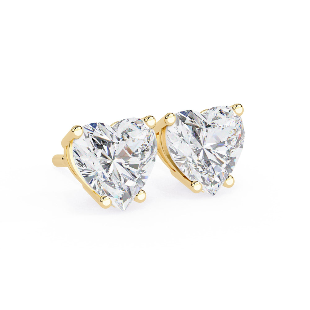 Heart-shaped diamond earrings with gold prongs on a white background