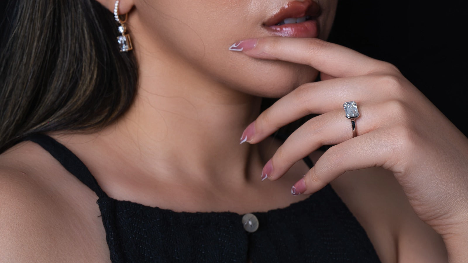 Close-up of a woman wearing a diamond ring with a dark background