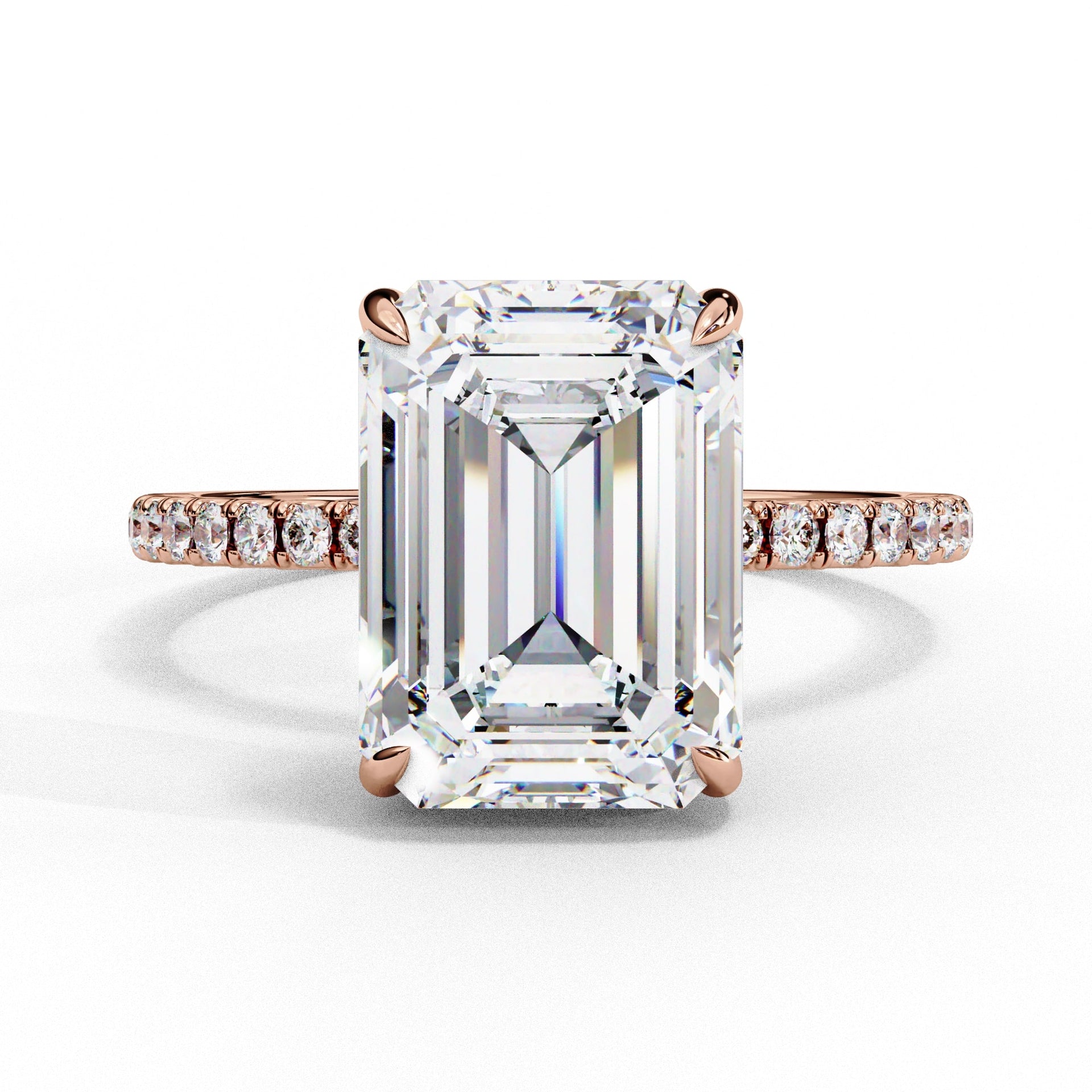 Diamond ring with emerald-cut center stone and rose gold band on white background