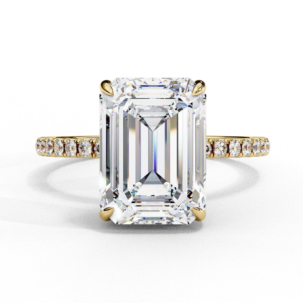 Diamond ring with emerald-cut center stone and gold band on a white background