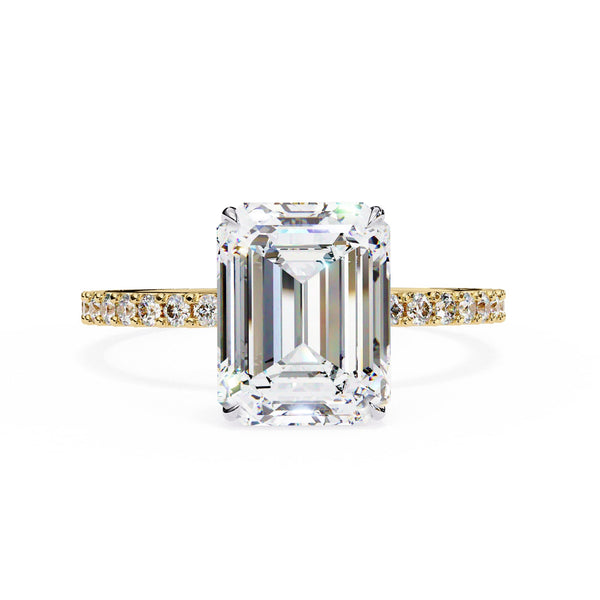 Diamond ring with emerald-cut center stone and gold band on a white background