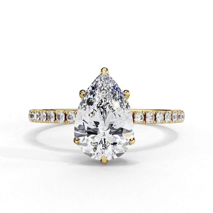 Gold ring with a pear-shaped diamond and smaller diamonds on the band against a white background