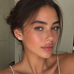 Close-up of a woman with styled hair and earrings indoors.