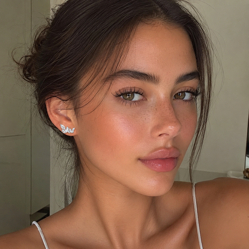 Close-up of a woman with styled hair and earrings indoors.