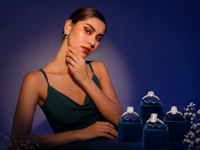 Woman wearing jewelry with diamond rings in blue boxes on a dark background