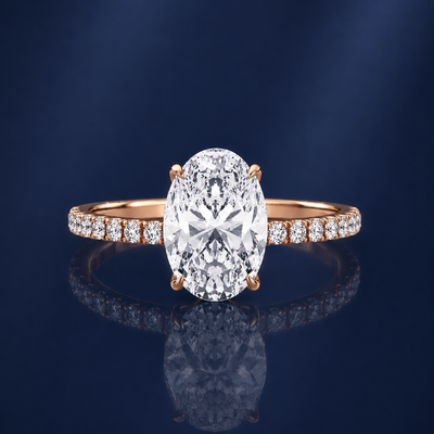 Rose gold ring with a large diamond and smaller diamonds on the band against a dark blue background