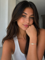 Woman wearing a white sleeveless top with a gold bracelet, indoors.