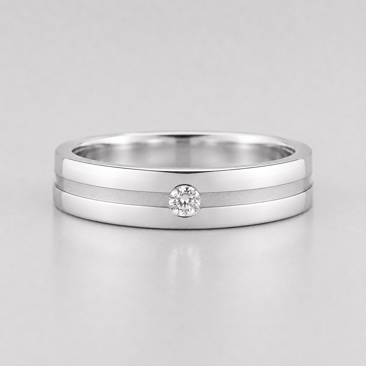 Round lab grown diamond flush set engagement ring for men featuring a satin center groove with a single flush set round diamond in a polished white gold band.