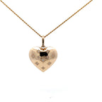 Gold heart-shaped pendant necklace with engraved details on a white background