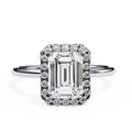 Diamond ring with emerald-cut center stone and halo on a white background