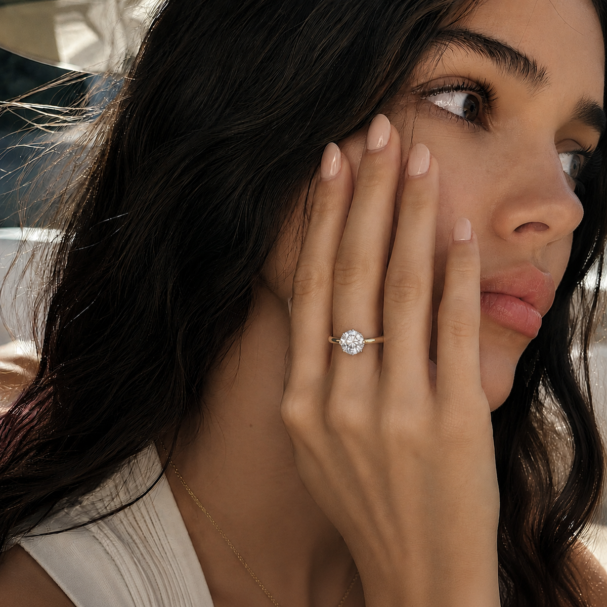 A woman wearing a round brilliant cut solitaire ring made with a yellow gold band.