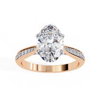 Rose gold ring with a large pear-shaped diamond and smaller diamonds on the band against a white background