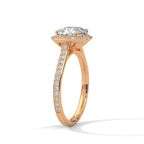 Angled side view of a cushion cut diamond halo engagement ring in rose gold with a pavé diamond band and raised gallery setting.