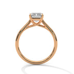 Side profile of an emerald cut diamond solitaire engagement ring in rose gold with a raised four-prong setting and open gallery.