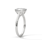 Angled side view of an emerald cut diamond solitaire engagement ring in white gold with a raised four-prong setting and plain band.