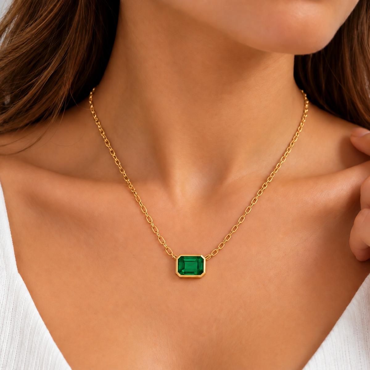 Woman wearing an emerald cut green gemstone pendant necklace in yellow gold