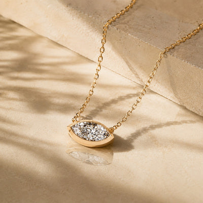 Gold necklace with a diamond pendant on a beige fabric background