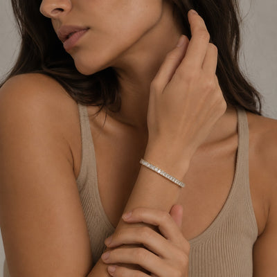 Woman wearing a silver bracelet on her wrist, with a neutral background