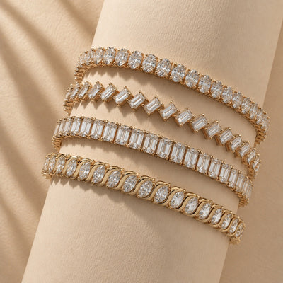 Three gold bracelets with diamond accents on a beige surface