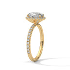 Angled side view of an oval cut diamond halo engagement ring in yellow gold with a pavé diamond band and raised halo setting.