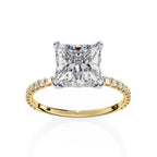 Gold ring with a large diamond and smaller diamonds on the band against a white background