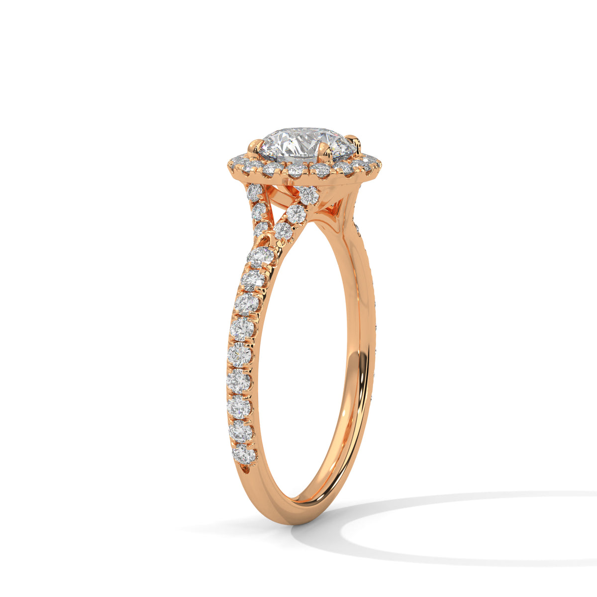 Angled side view of a round cut diamond halo engagement ring in rose gold with a pavé diamond band and diamond-accented gallery.
