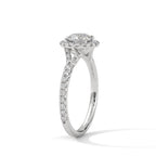 Angled side view of a round cut diamond halo engagement ring in white gold with a pavé diamond band and diamond-accented gallery.