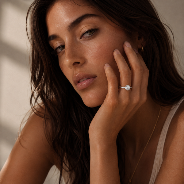 Woman wearing a round cut diamond halo engagement ring in white gold with a pavé diamond band in a close-up lifestyle shot.