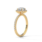 Angled side view of a round cut diamond halo engagement ring in yellow gold with a pavé diamond band and raised halo setting.