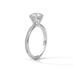 Side angle of a round cut diamond engagement ring in yellow gold with a raised prong setting and pave diamond band.