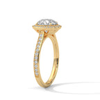Angled side view of a round cut diamond halo engagement ring in yellow gold with a pavé diamond band and raised setting.