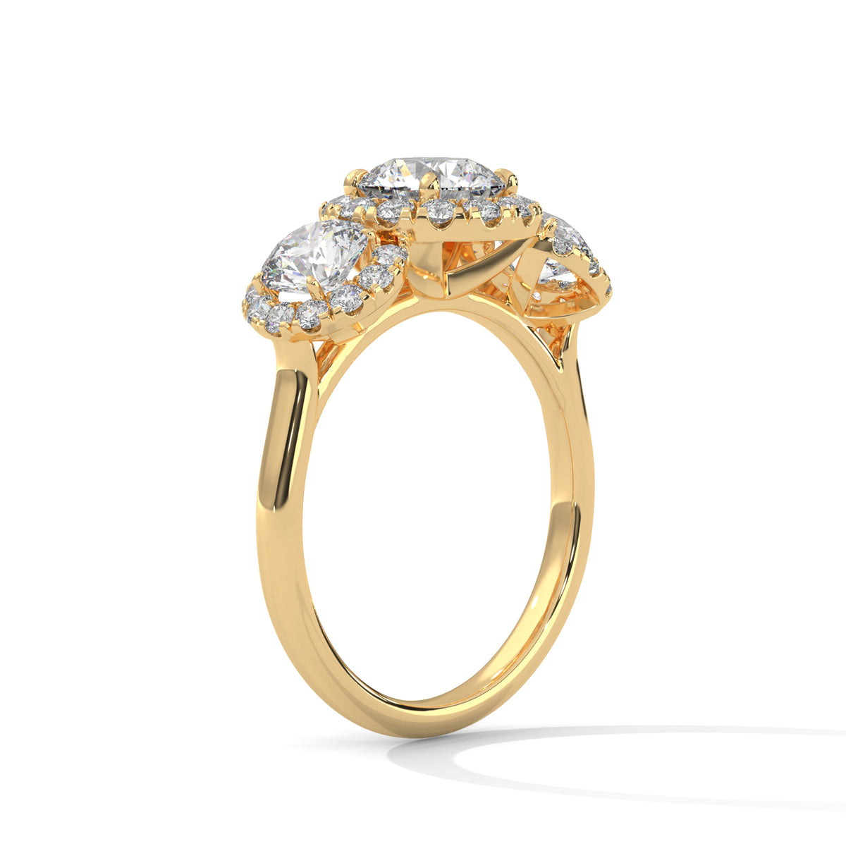 Angled side view of a three-stone round cut diamond halo engagement ring in yellow gold with raised gallery settings and a plain band.